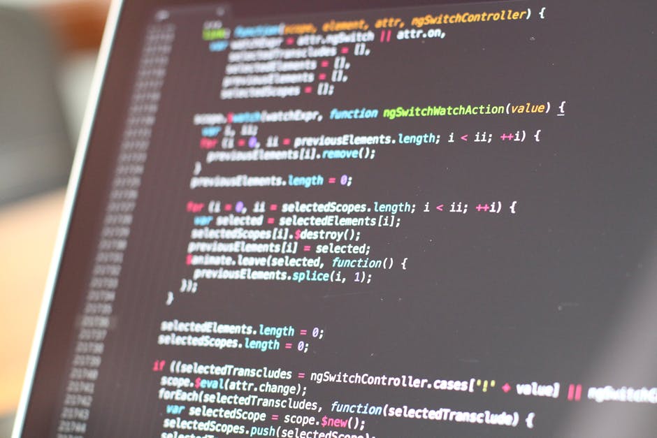 A close-up view of a computer screen displaying lines of colorful code, including keywords and syntax highlighted in shades of blue, pink, green, and white. The background is slightly blurred to empha